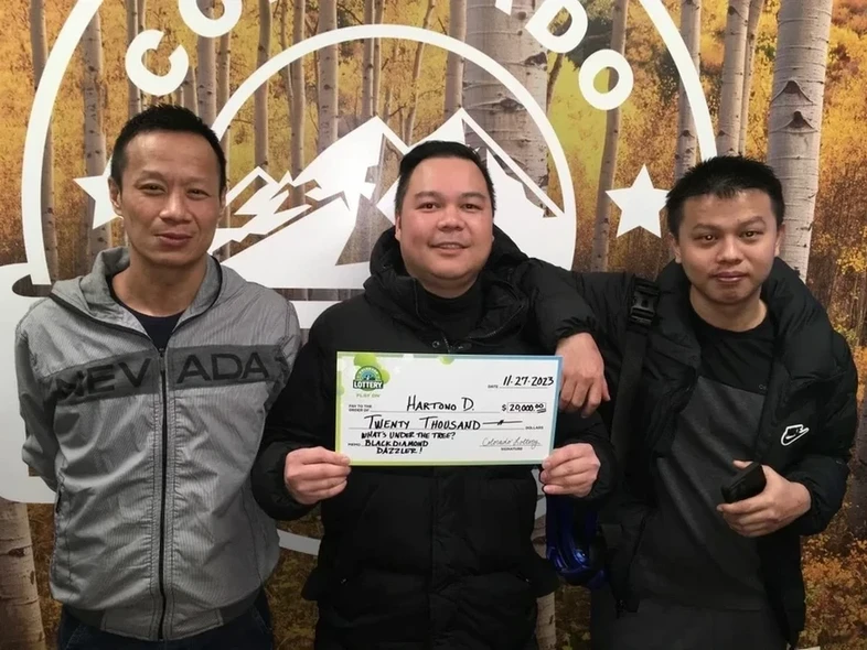 Hartono D. 手持他的 $20,000中奖支票，背景为科罗拉多彩票